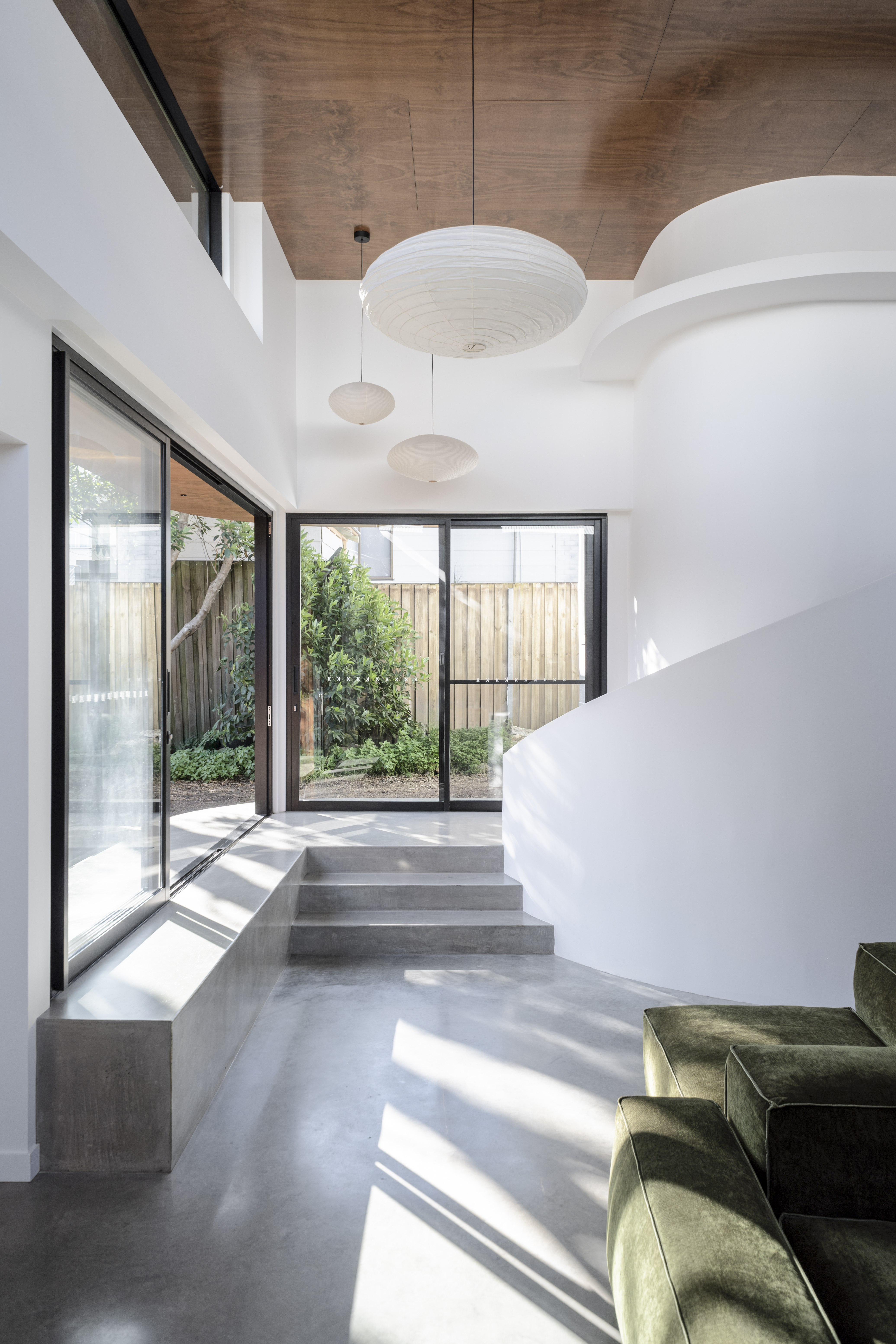 Living space — sliding doors to garden, curved white wall and pendant lights
