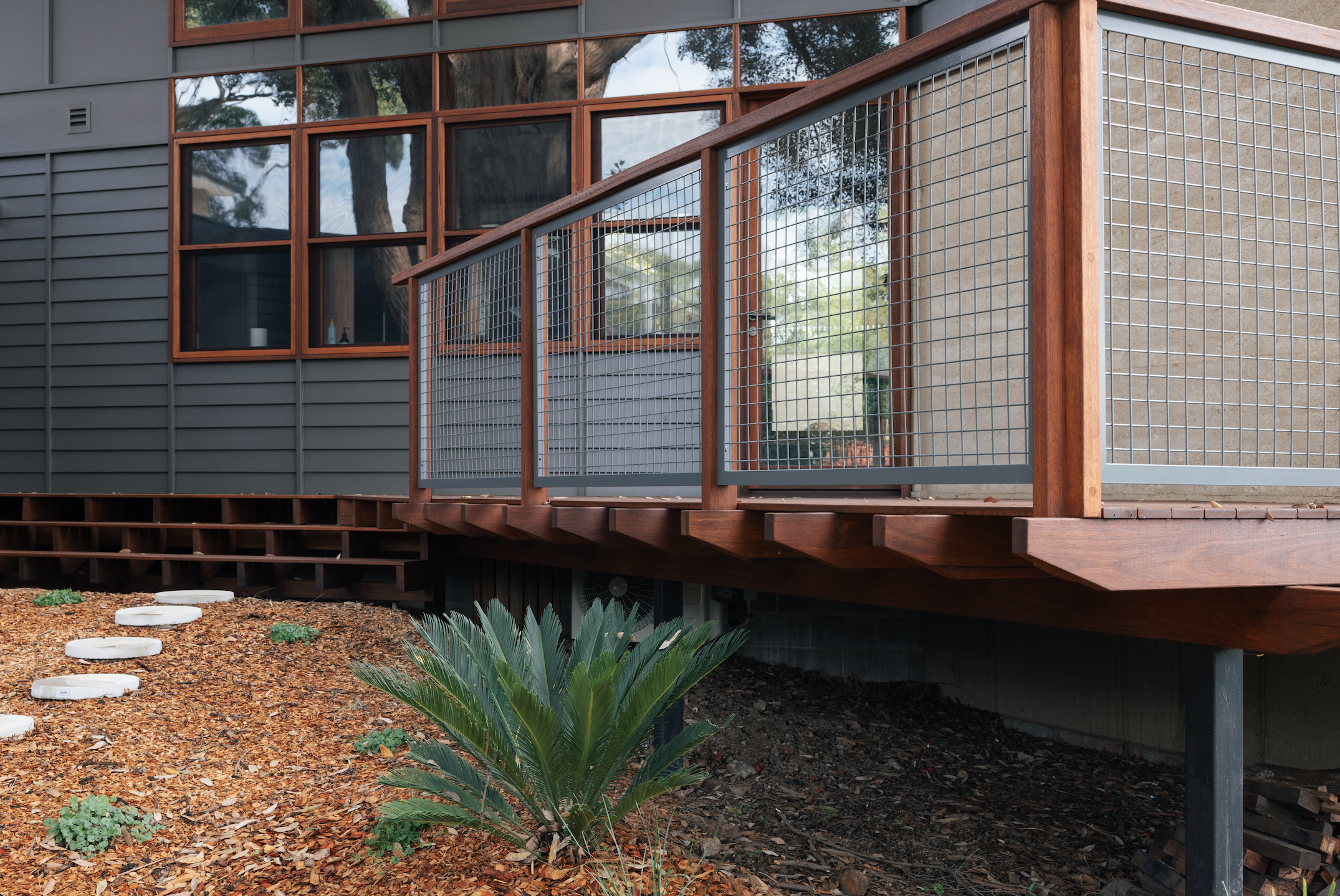 Exterior detail — hardwood deck balustrade with mesh panels and native landscaping