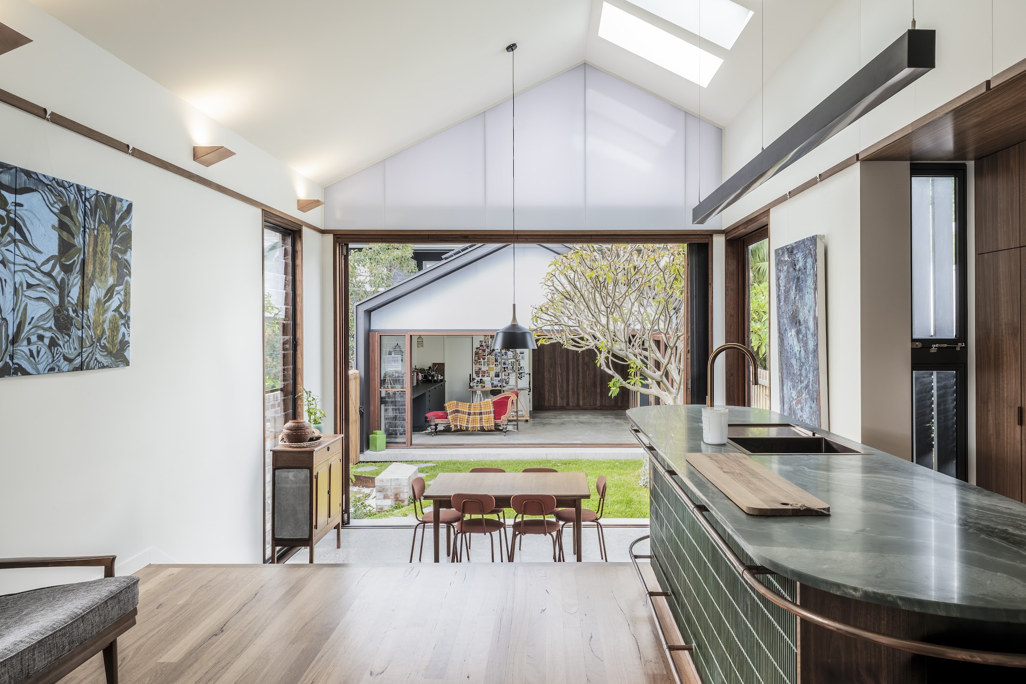Dianella — open-plan kitchen and living with vaulted ceiling, skylights and garden outlook through bifold doors