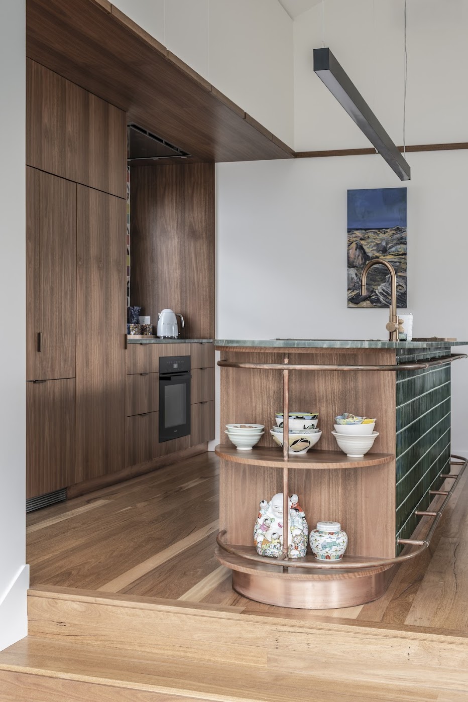 Kitchen end detail — curved copper shelving with ceramics, walnut pantry and oven niche