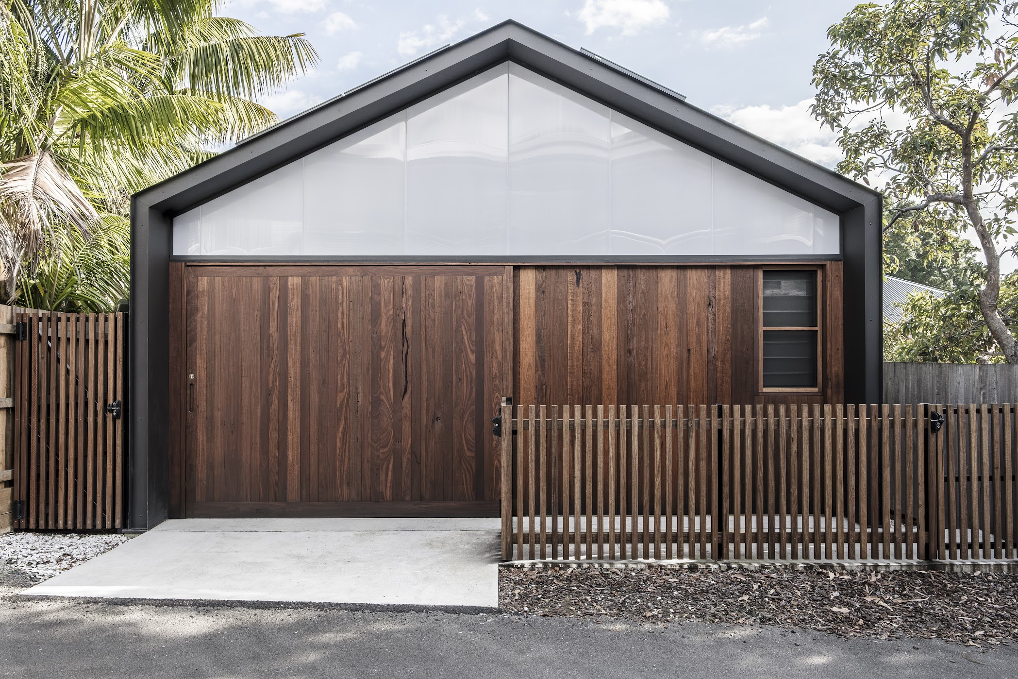 Garage and studio — timber barn doors, polycarbonate gable, timber picket fence