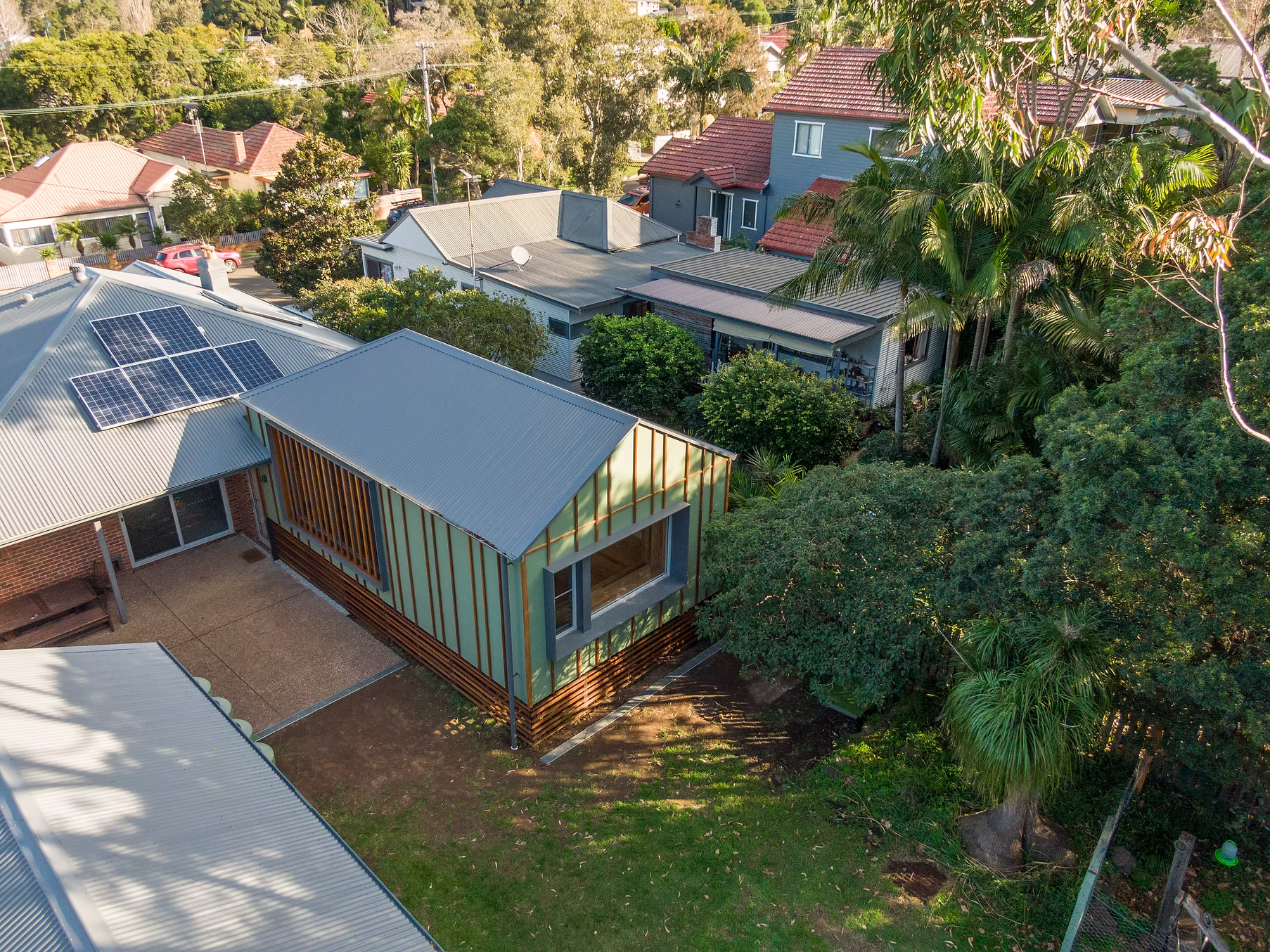 Lachlan St — aerial view of raised timber-clad addition with green cladding and solar panels